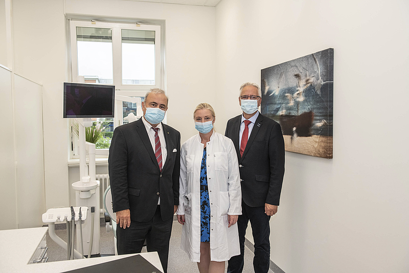 Drei Männer mit Anzug und Mundschutz im Zahnarztbehandlungszimmer